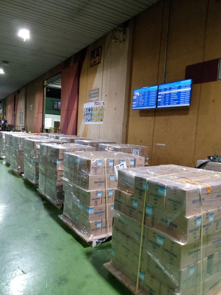 Kargo udara tersusun di gudang regulated agent dengan layar informasi penerbangan